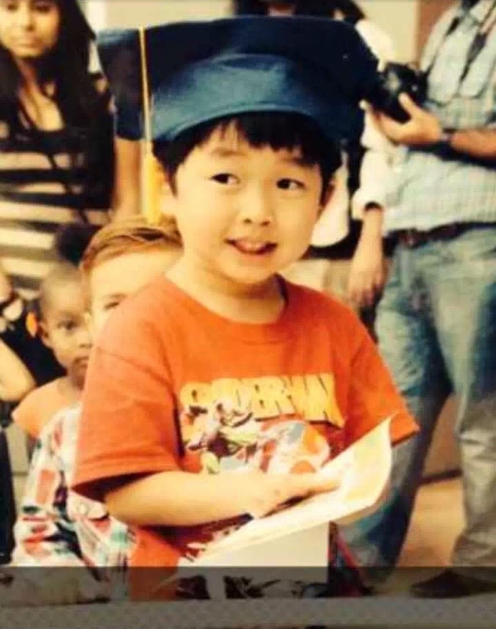 Jonathan Wang as a child wearing a graduation cap and Spider-Man shirt at kindergarten graduation