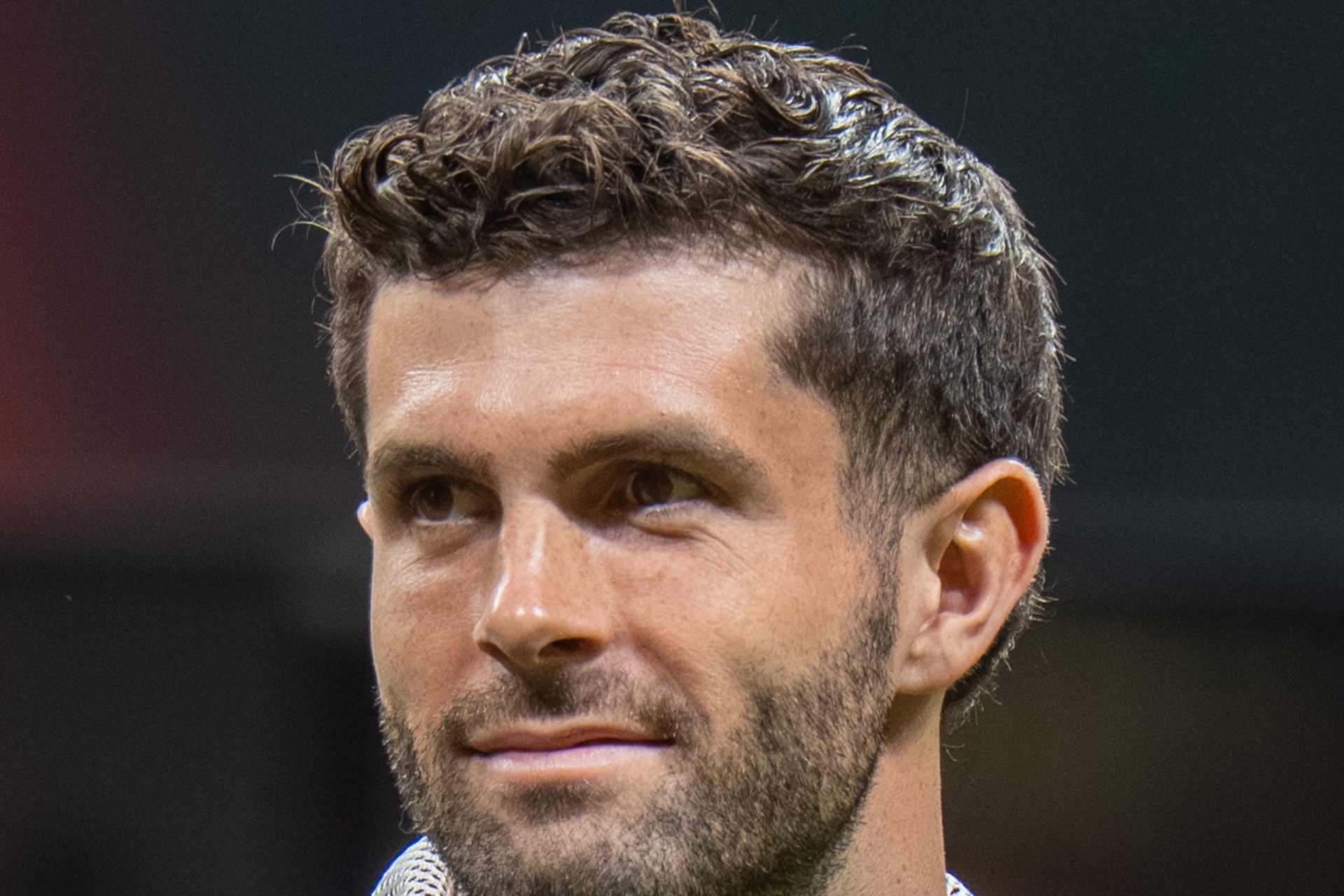 Close-up of Christian Pulisic wearing a red United States national team warm-up jacket.