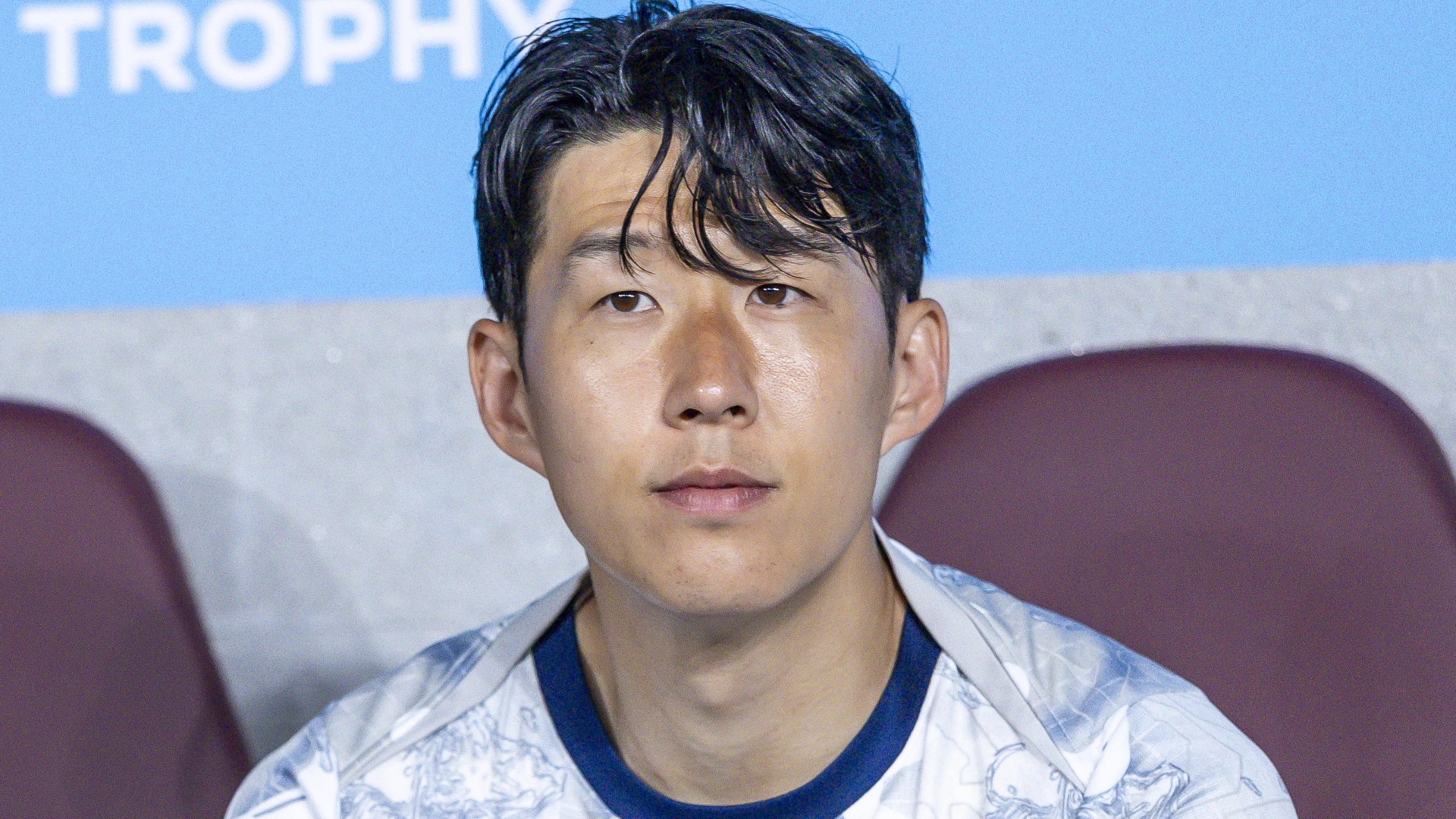Son Heung-Min seated on the South Korea bench during an international football match.
